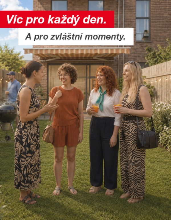 Skupina lidí si povídá a užívá nápoje v zahradě za domem s dřevěným plotem a světelnými řetězy.