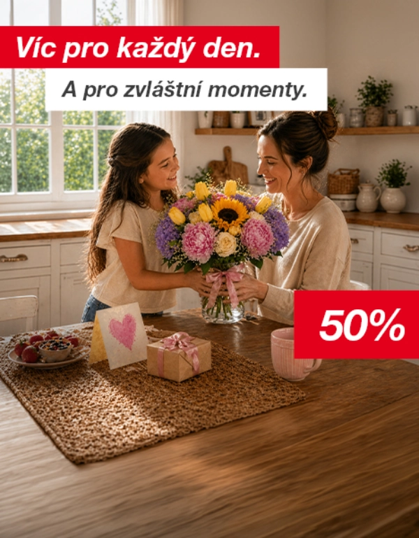 Žena a dívka sedí u kuchyňského stolu s kyticí květin, dárkovou krabičkou, přáním a hrnkem.