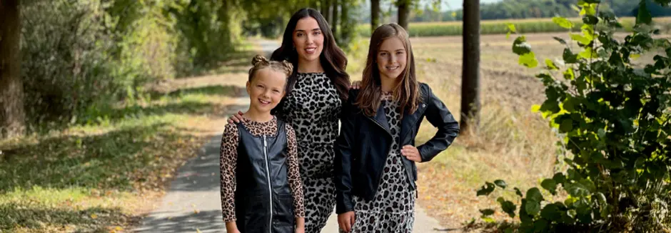 Drei Personen stehen gemeinsam in stylischen Outfits mit Leopardenmuster
