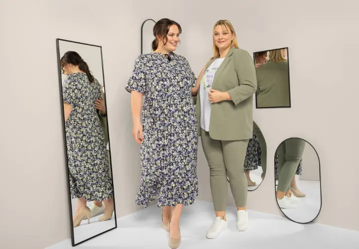 Zwei Frauen stehen in einer stilvollen Umgebung mit Spiegeln und präsentieren ein geblümtes Kleid und ein schickes grünes Outfit, das Selbstbewusstsein und Eleganz ausstrahlt. Zwei Frauen stehen in einer stilvollen Umgebung mit Spiegeln und präsentieren ein geblümtes Kleid und ein schickes grünes Outfit, das Selbstbewusstsein und Eleganz ausstrahlt.