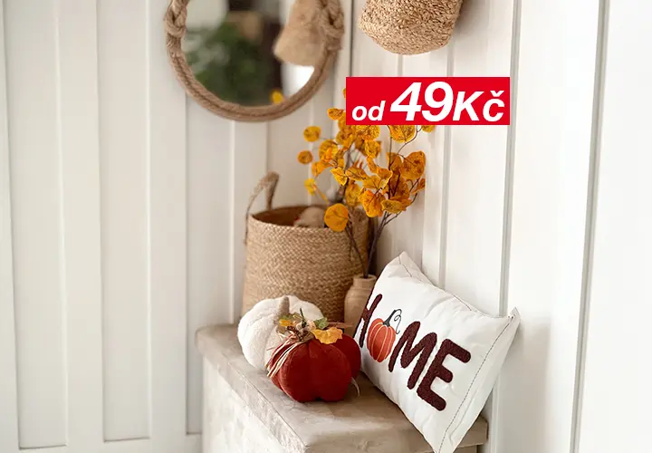 Útulný interiér s kulatým zrcadlem, proutěnými košíky, podzimním listím a dekorativním polštářem s nápisem „HOME“ a dýňovým motivem.