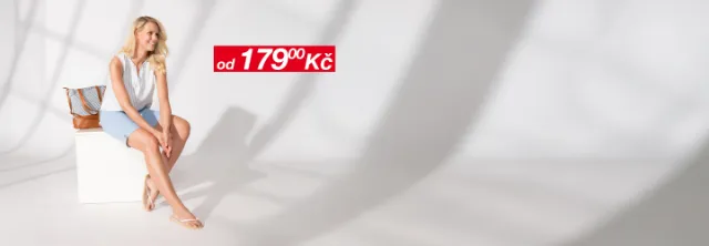 Žena má na sobě lehkou letní blůzu a džínové kraťasy, šťastně se usmívá.