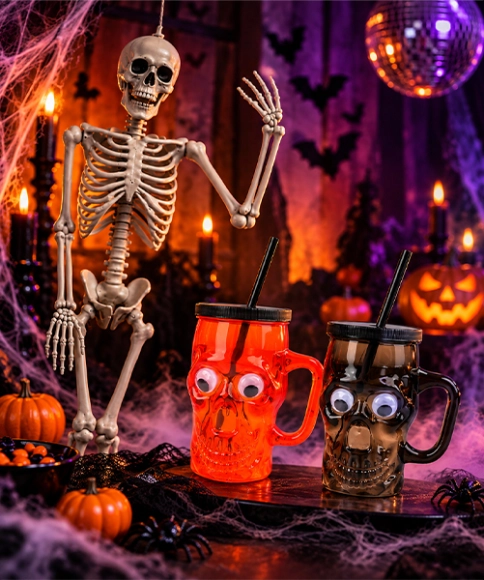 Halloweenská dekorace s kostrou a hrnky ve tvaru lebky