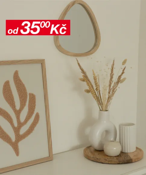 Minimalistický dekor s malým zrcadlem, zarámovaným listovým uměním a vázou se sušenými květinami na dřevěném podnosu, na pozadí neutrální stěny.