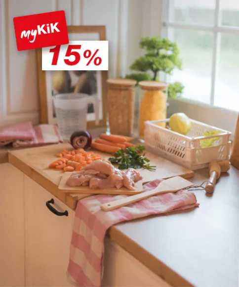 Světlá kuchyňská linka s kuřecími prsíčky, nakrájenou mrkví, bylinkami a různými ingrediencemi ve sklenicích připravenými k vaření.