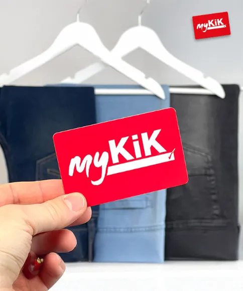 Ruka drží červenou věrnostní kartu myKiK před zavěšenými džínami různých odstínů.