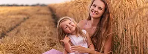 Dívka sedí se svou ženou na zlatém pšeničném poli a dívá se do teplého západu slunce.